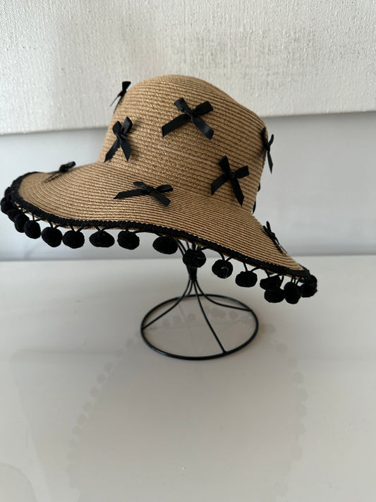 Beige straw hat with black decorative elements on a white background