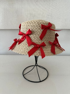 Woven hat with red ribbons on a mannequin against a light background